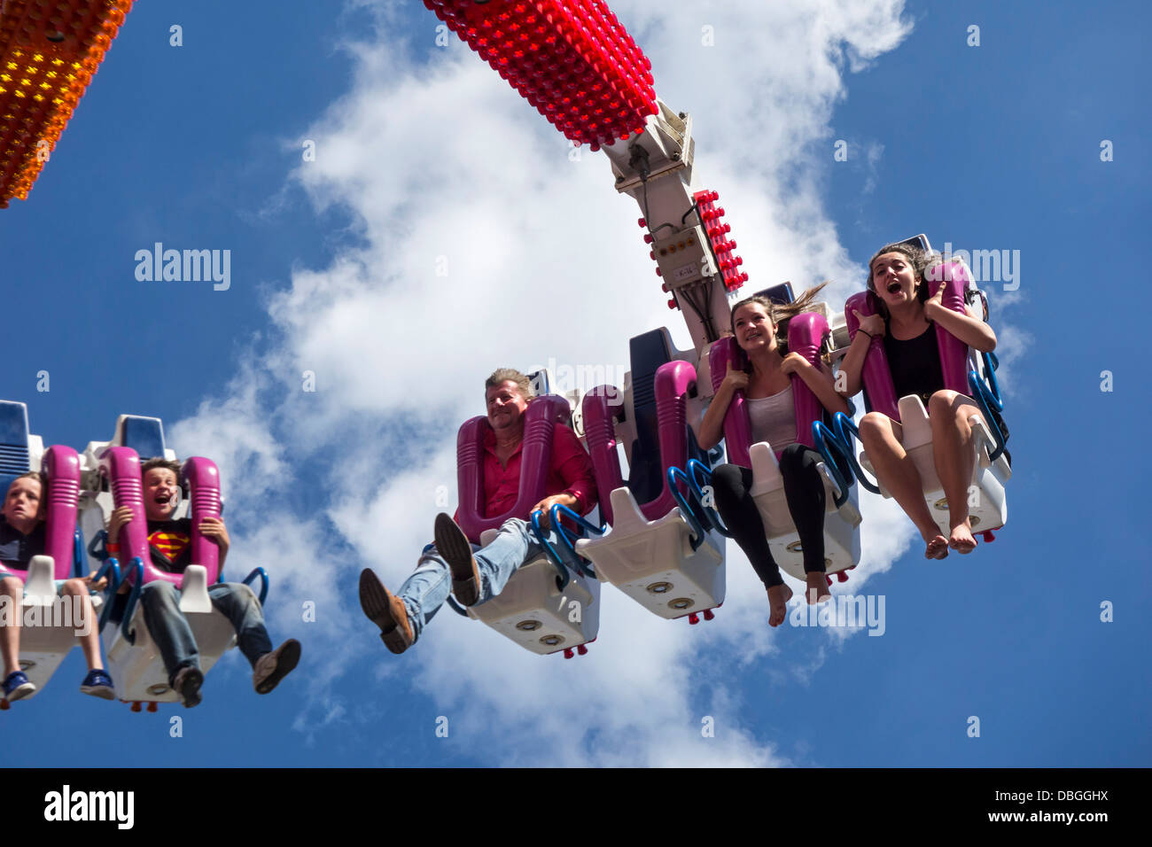 Excited thrillseekers / thrill seekers having fun on fairground attraction G Force at travelling funfair / traveling fun fair Stock Photo