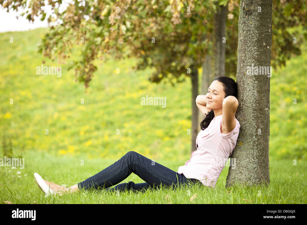 Young dark haired girl leaning  against a tree Stock Photo