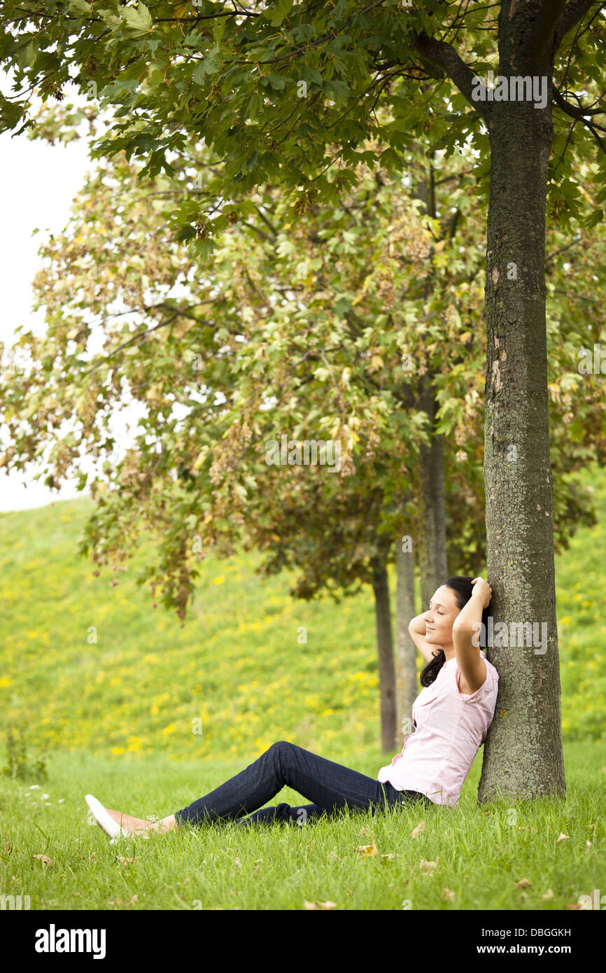 Young dark haired girl leaning  against a tree Stock Photo