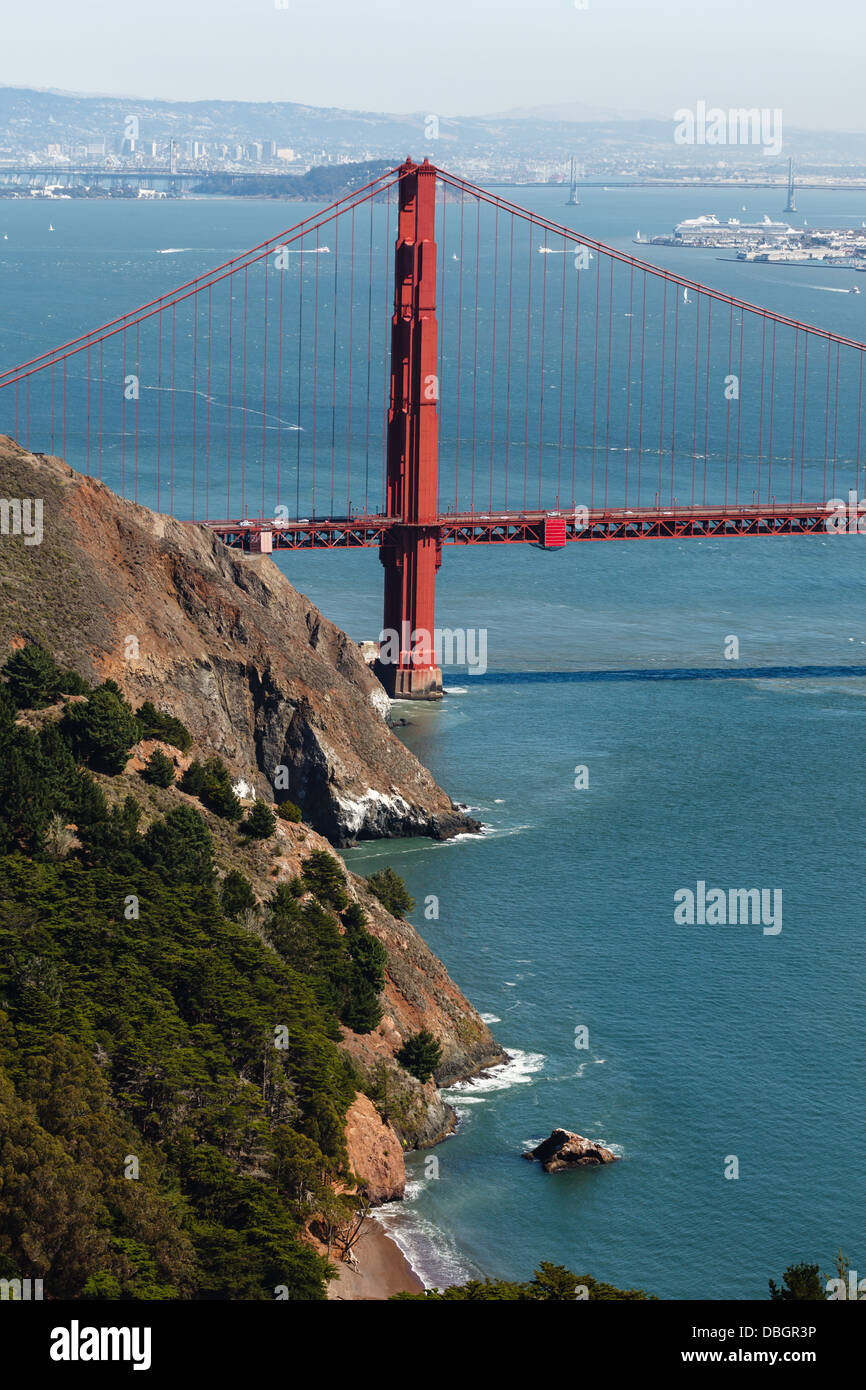 Tower of Golden Gate Bridge and across San Francisco Bay to Oakland framed by cliffs on a sunny day Stock Photo