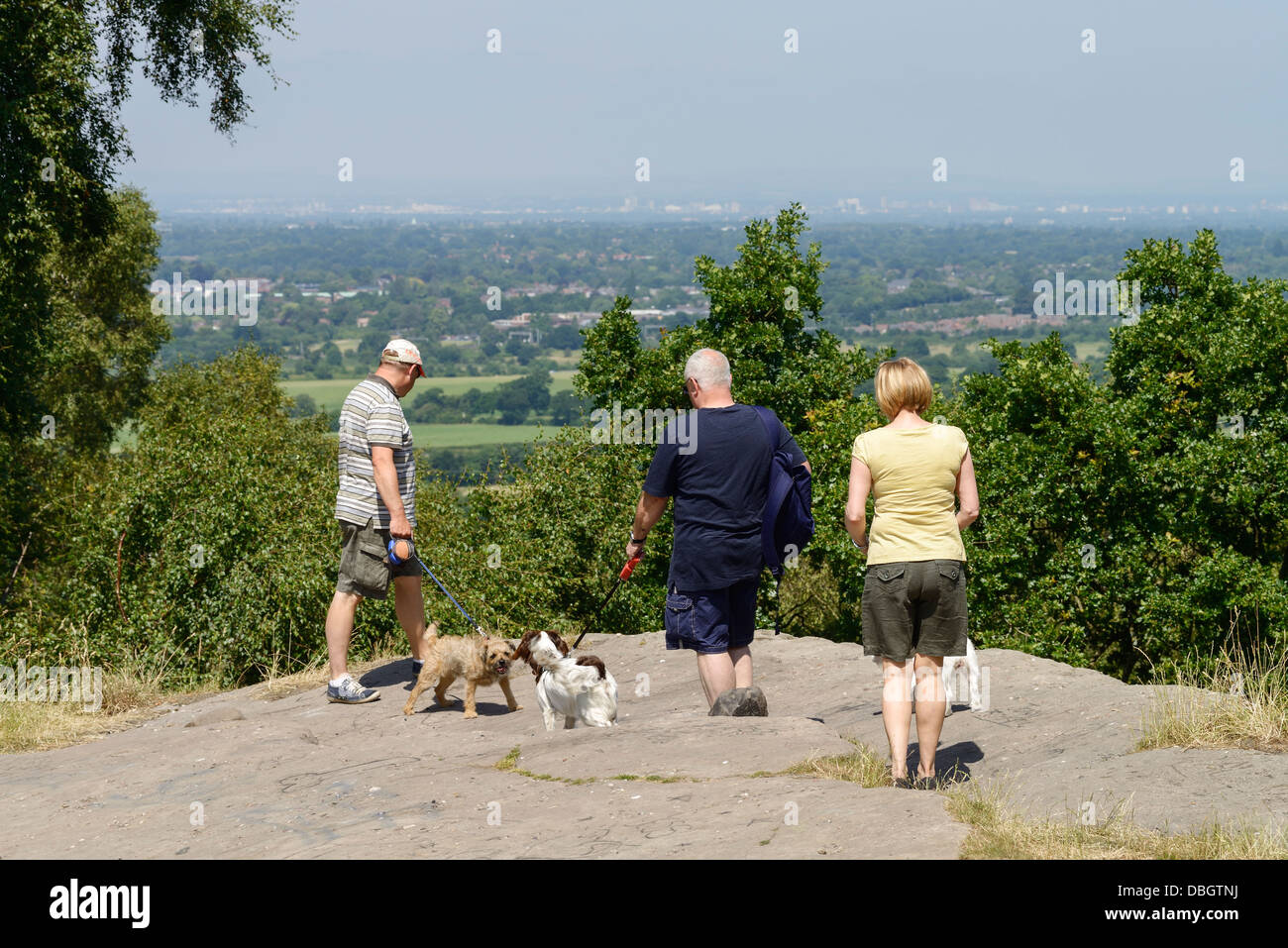 Dog walkers at Castle Rock near Alderley Edge Cheshire with the skyline of Manchester in the distance Stock Photo