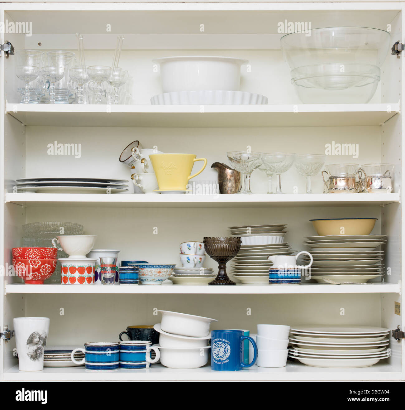 White kitchen cupboard with glasses, cups and bowls Stock Photo