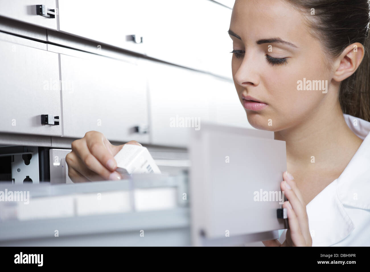 Young female pharmacist reaching for medicine Stock Photo