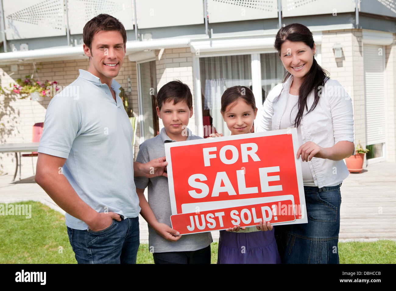 Family with a sale sign outside their new home Stock Photo - Alamy