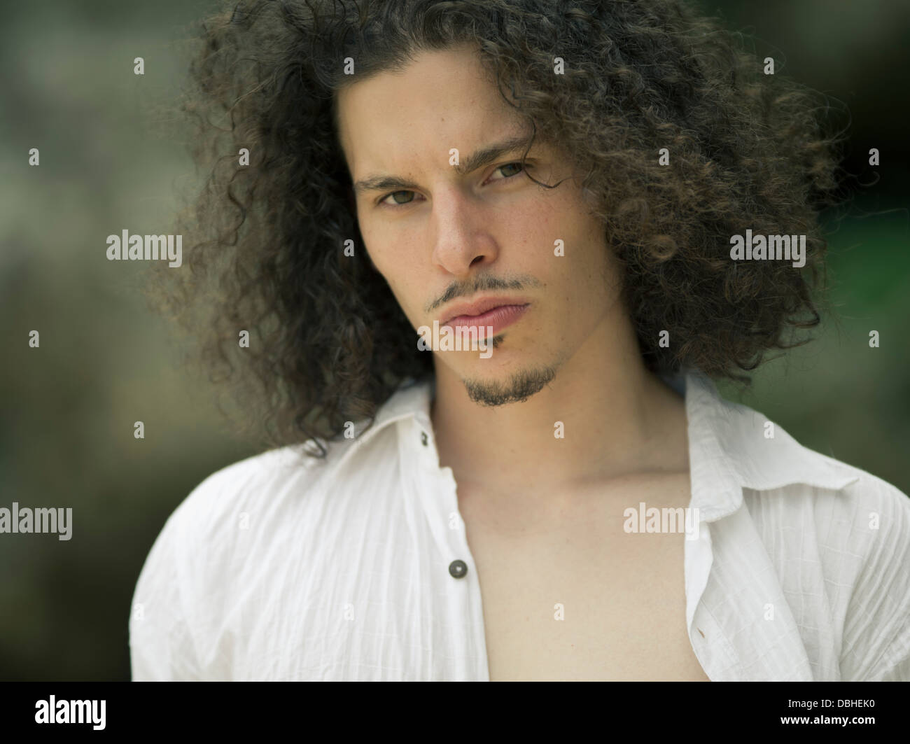 Egyptian American Man with long wavy hair beard and mustache wearing unbuttoned short sleeve white cotton shirt Stock Photo