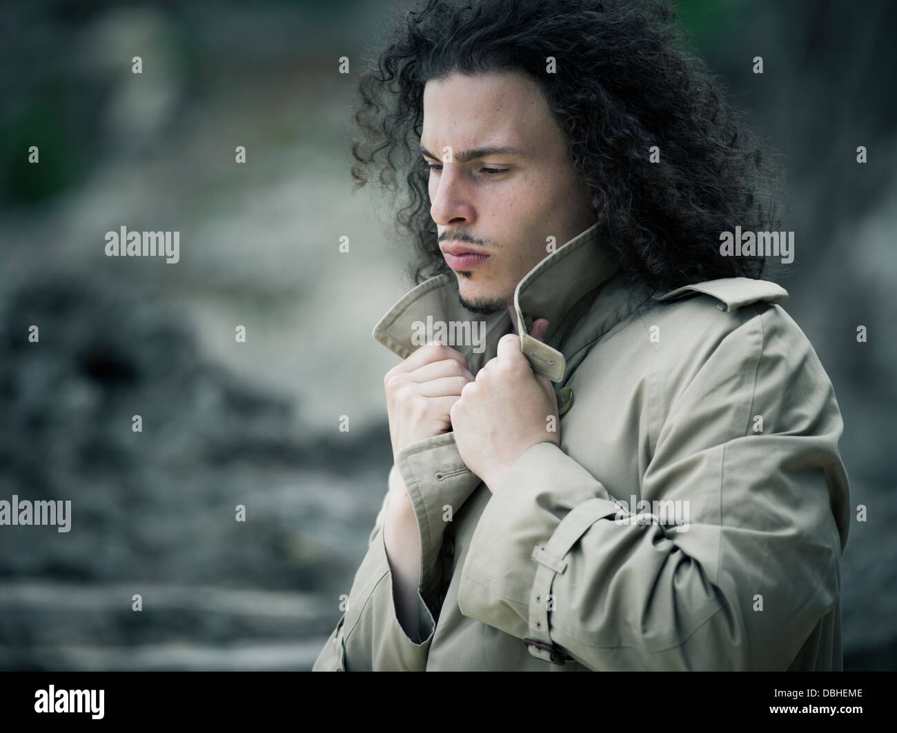 Man with long wavy hair beard and mustache wearing Burberry trench coat  raincoat Stock Photo