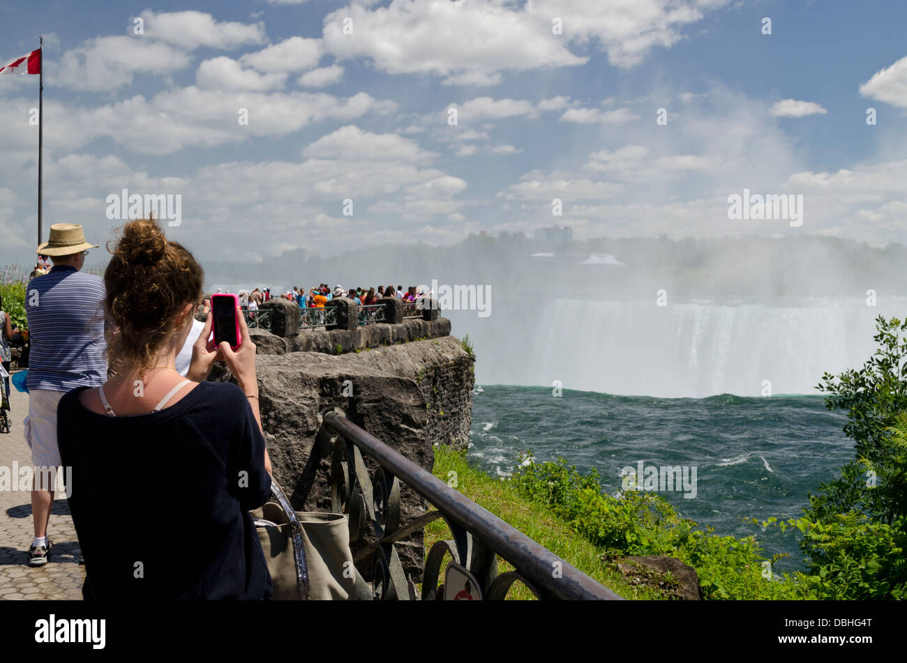 A woman takes photos of Niagara Falls using her cell phone camera. Many