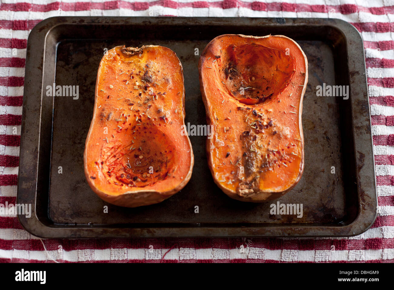 Cooked and seasoned butternut squash on a baking sheet, rustic delicious food. Stock Photo