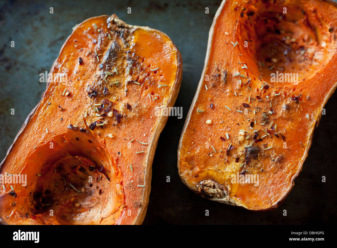 Cooked and seasoned butternut squash on a baking sheet, rustic delicious food. Stock Photo
