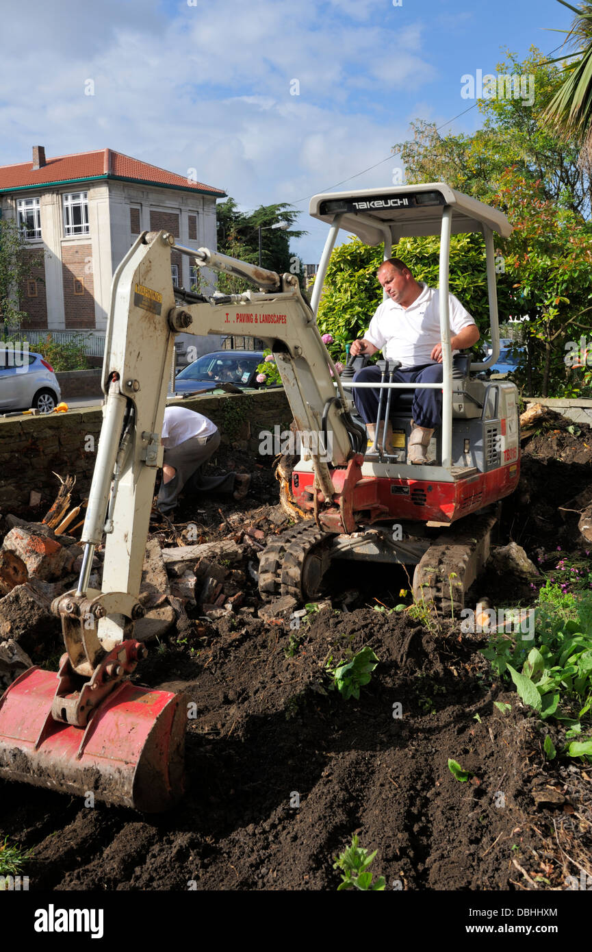 Mini digger removing earth in domestic garden Stock Photo
