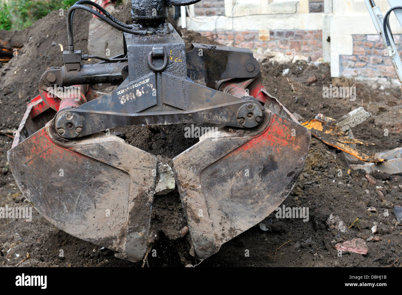 Clamshell grab bucket being used to remove soil and rubble Stock Photo