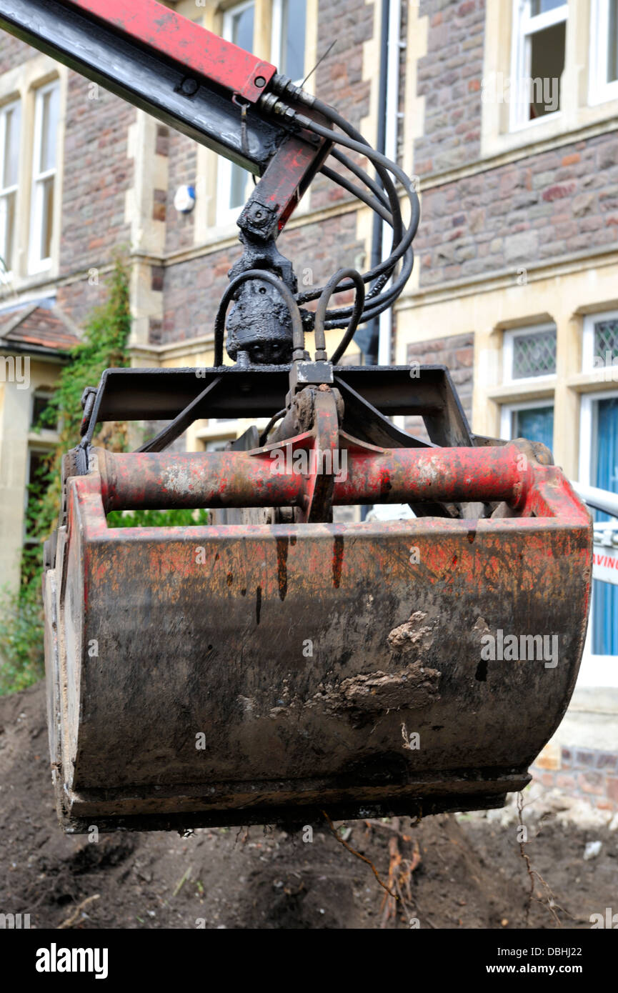 Clamshell grab bucket being used to remove soil and rubble in garden of house, UK Stock Photo