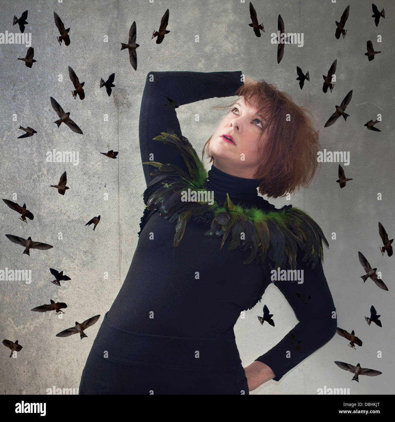 Woman surrounded by birds on a gray background. Stock Photo