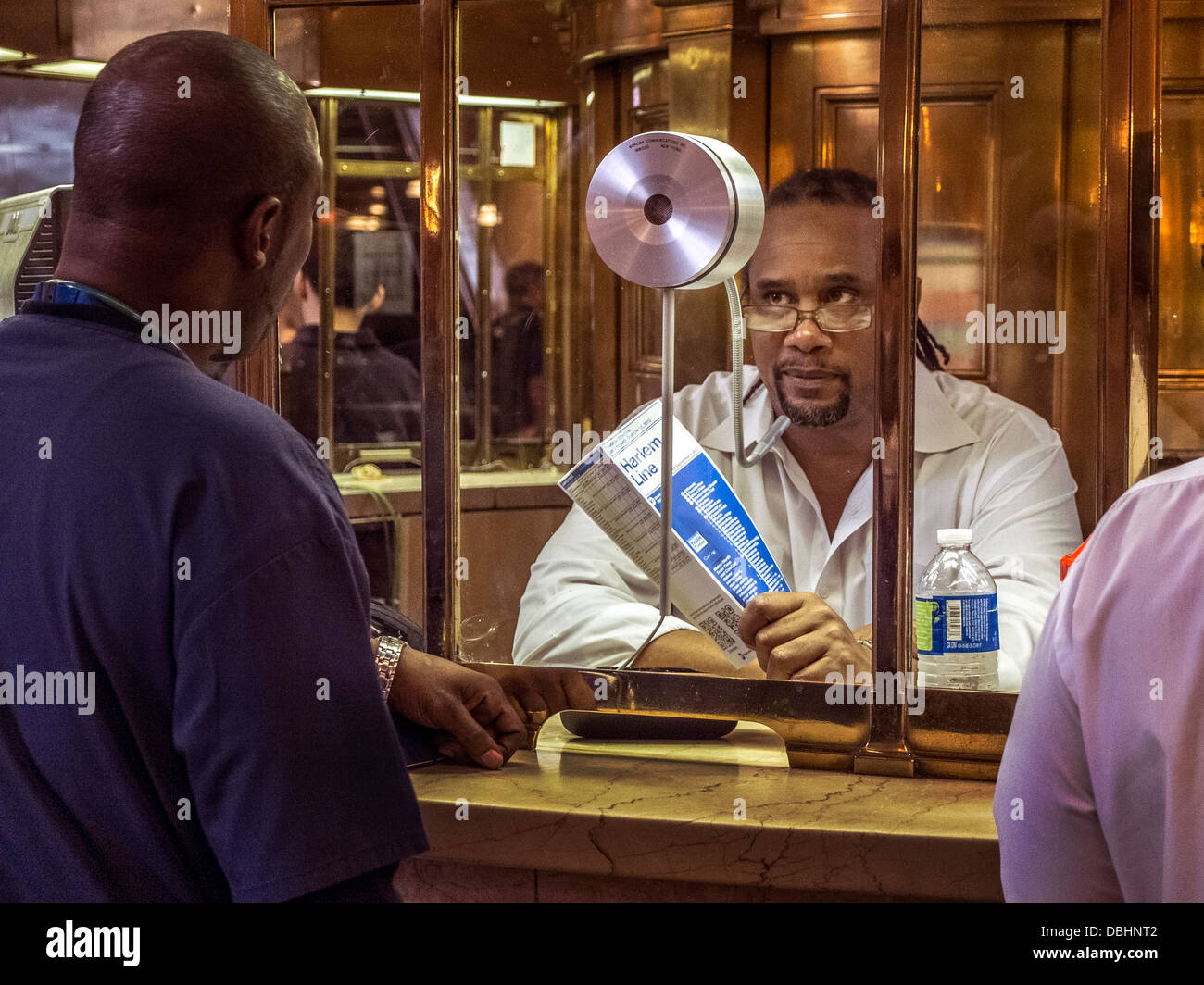 An African American railroad traveler seeks help from an African American at the information booth in Grand Central Station Stock Photo