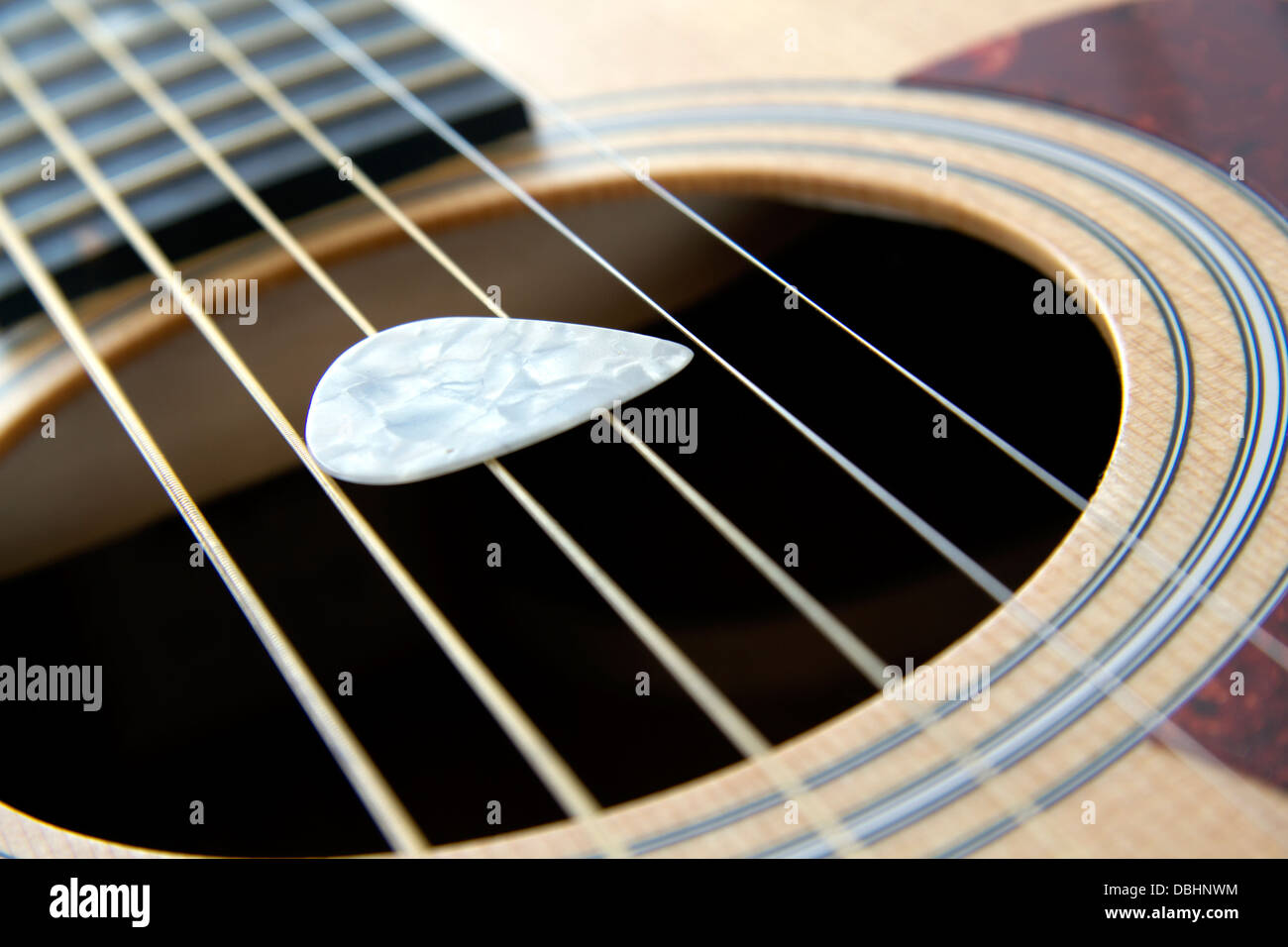 White plectrum on a 6 string acoustic guitar Stock Photo