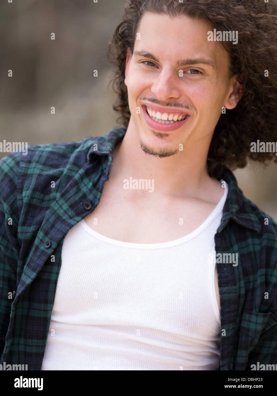 Egyptian American Man with long wavy hair beard and mustache smiling wearing check shirt and white t-shirt Stock Photo