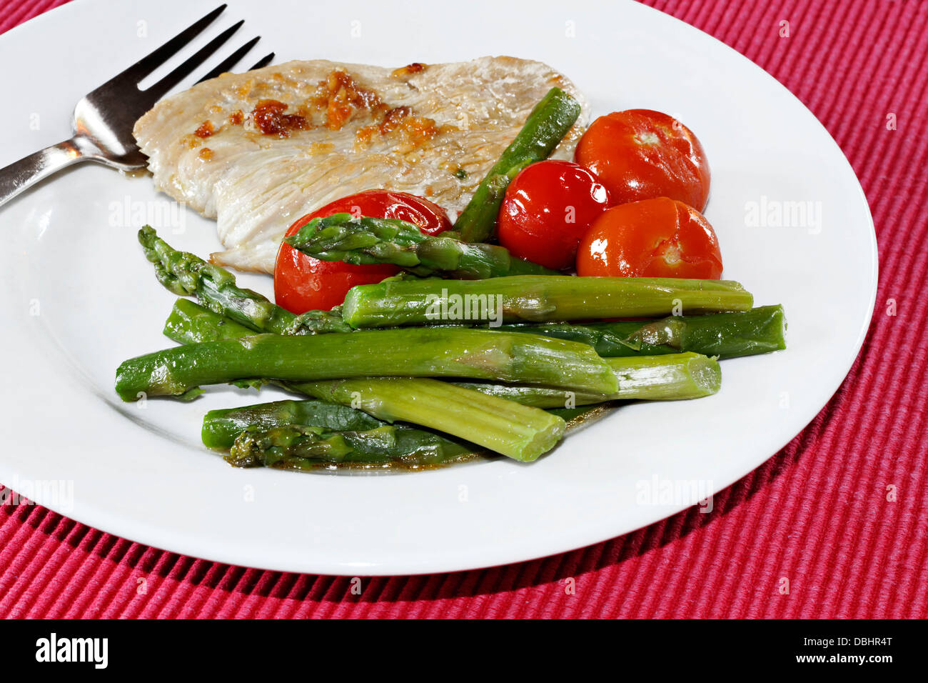 Turkey Steak, Green Asparagus and Tomatoes on white plate Stock Photo