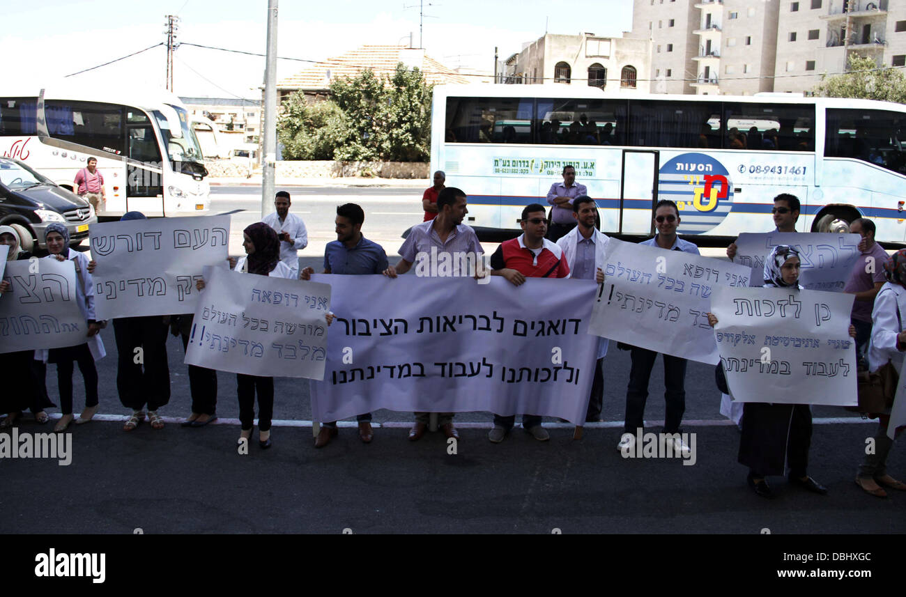 Jerusalem, West Bank, Palestinian Territory. 30th July, 2013. Palestinian students of medical colleges in Jerusalem's al-Quds University hold placards during a protest against the Israeli Health ministry demanding to confess of their certificates and allow them to work in Israeli hospitals, in front of Hadassah medical center, in Jerusalem July 31, 2013 Credit:  Saeed Qaq/APA Images/ZUMAPRESS.com/Alamy Live News Stock Photo