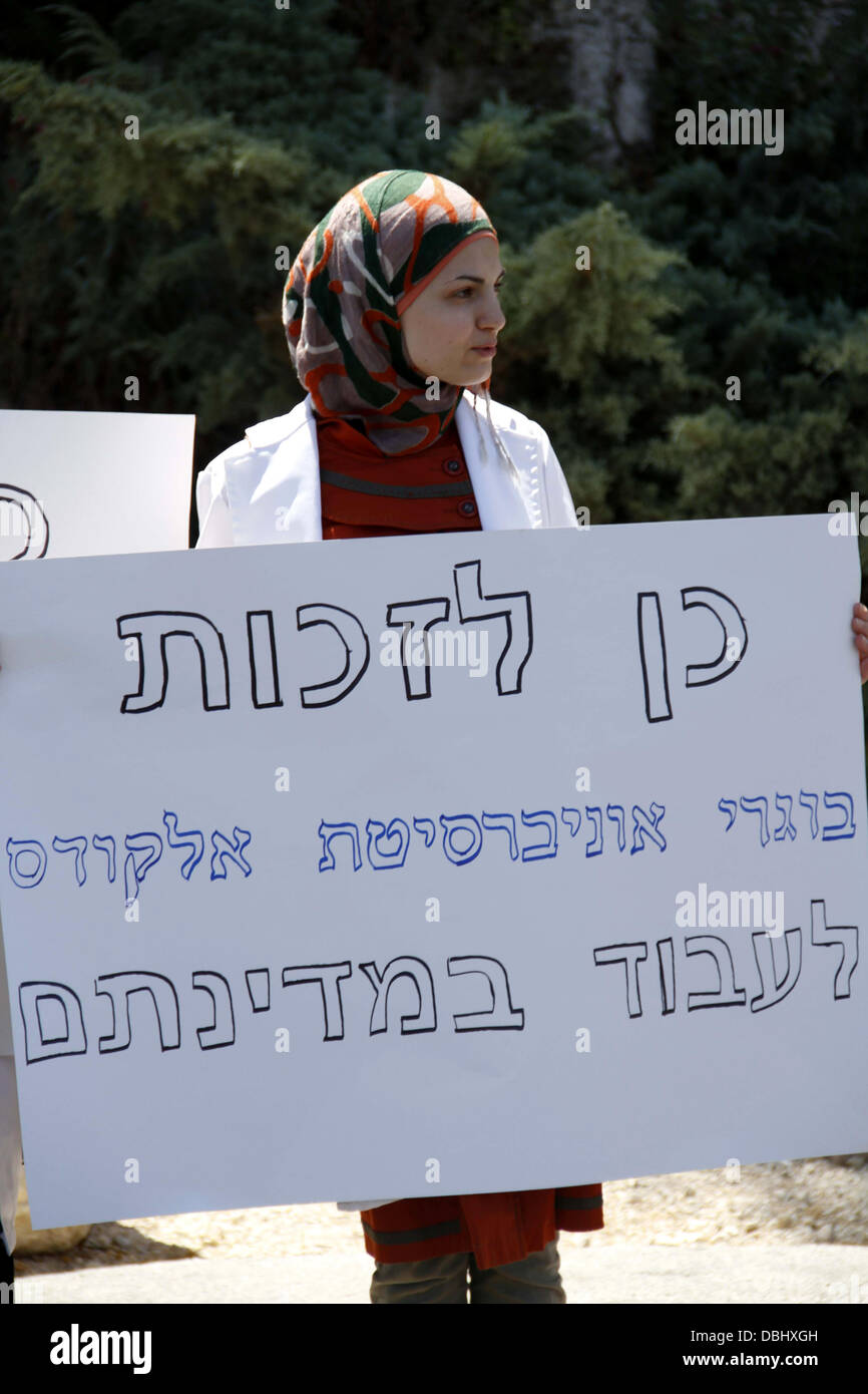 Jerusalem, West Bank, Palestinian Territory. 30th July, 2013. A Palestinian student of medical colleges in Jerusalem's al-Quds University holds a placard during a protest against the Israeli Health ministry demanding to confess of their certificates and allow them to work in Israeli hospitals, in front of Hadassah medical center, in Jerusalem July 31, 2013 Credit:  Saeed Qaq/APA Images/ZUMAPRESS.com/Alamy Live News Stock Photo