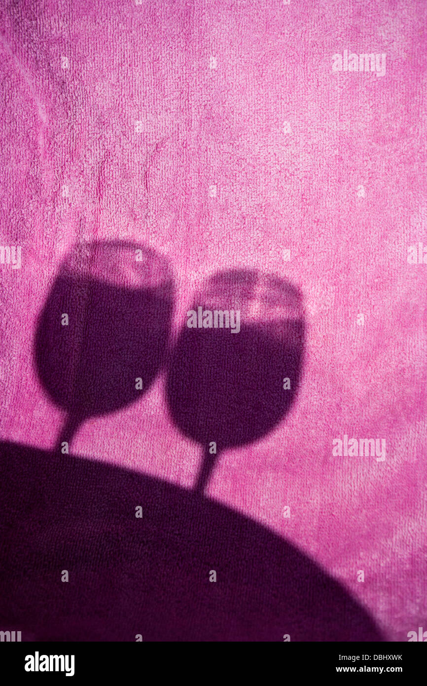 abstract shallow focus image of shadows of two wine glasses on a pink beach towel with focus on towel. Stock Photo