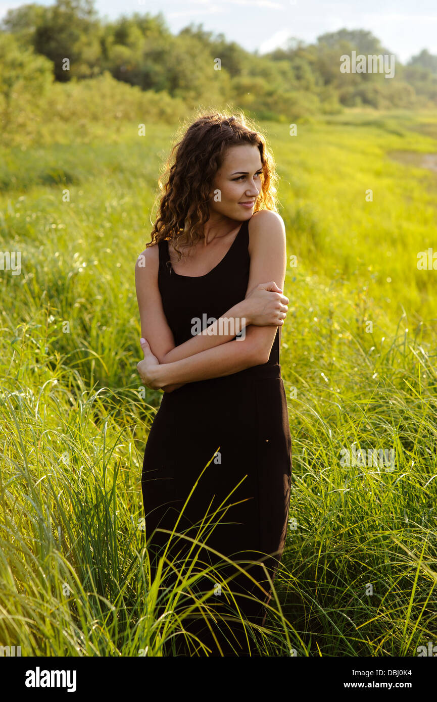 Beautiful girl walks and dreams in high grass on the banks of river ...