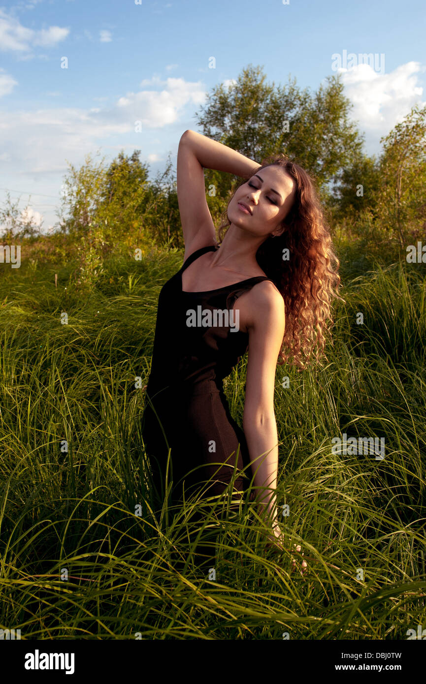 Beautiful girl walks and dreams in high grass on the banks of river ...