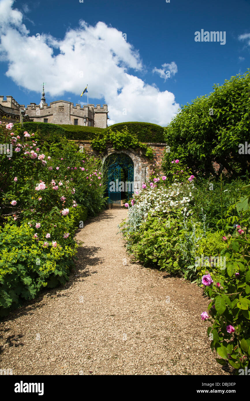 A glimpse of Rousham House from within the walled garden, with its wide herbaceous borders and gravel path and open garden gate, Oxfordshire, England Stock Photo
