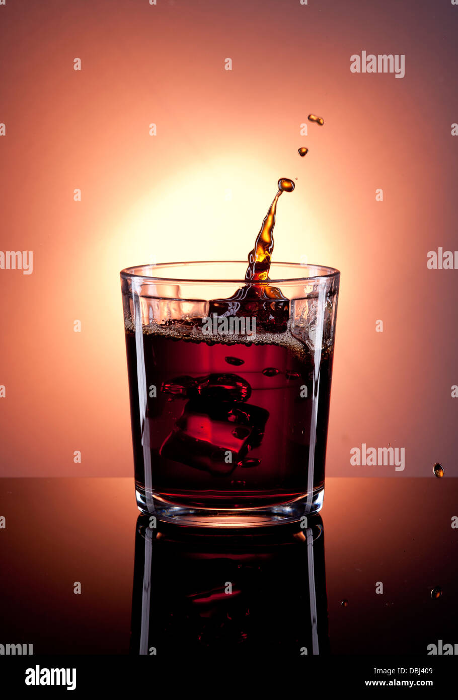 Ice cubes dropped into a glass of liquor make a splash. Stock Photo