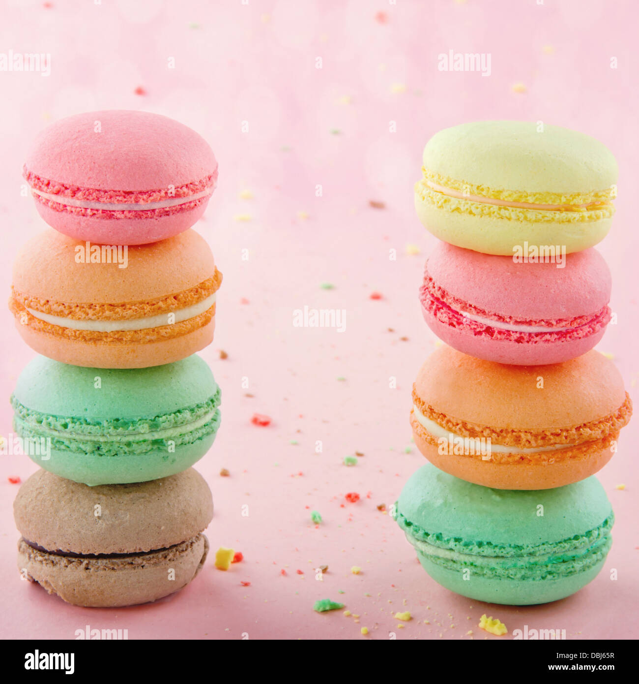 Two piles of colorful macaroons on pastel pink background with small ...
