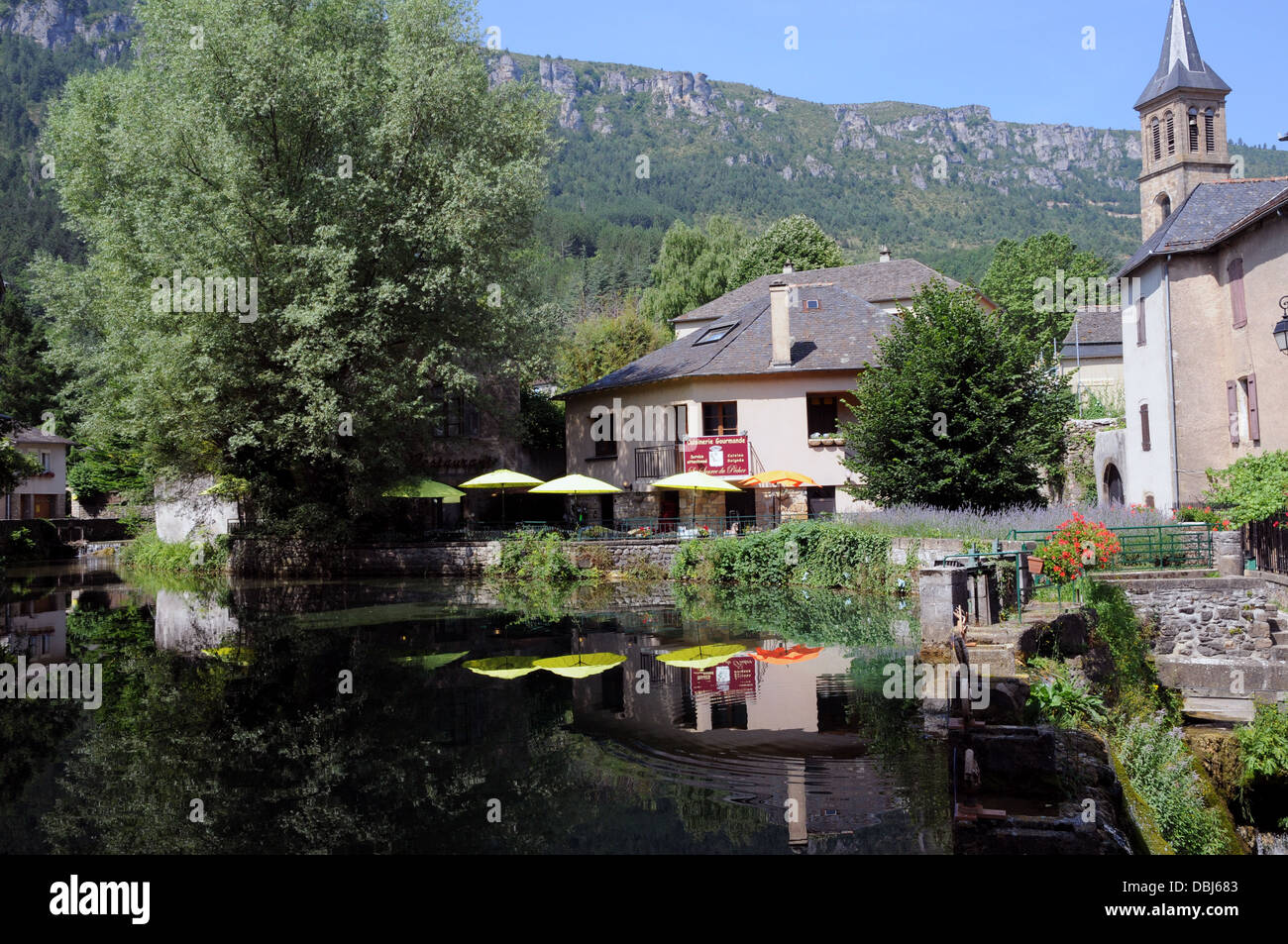 Umbrellas from the La Source de Pecher restaurant are reflected in the crystal clear waters of the Vibron river. Stock Photo