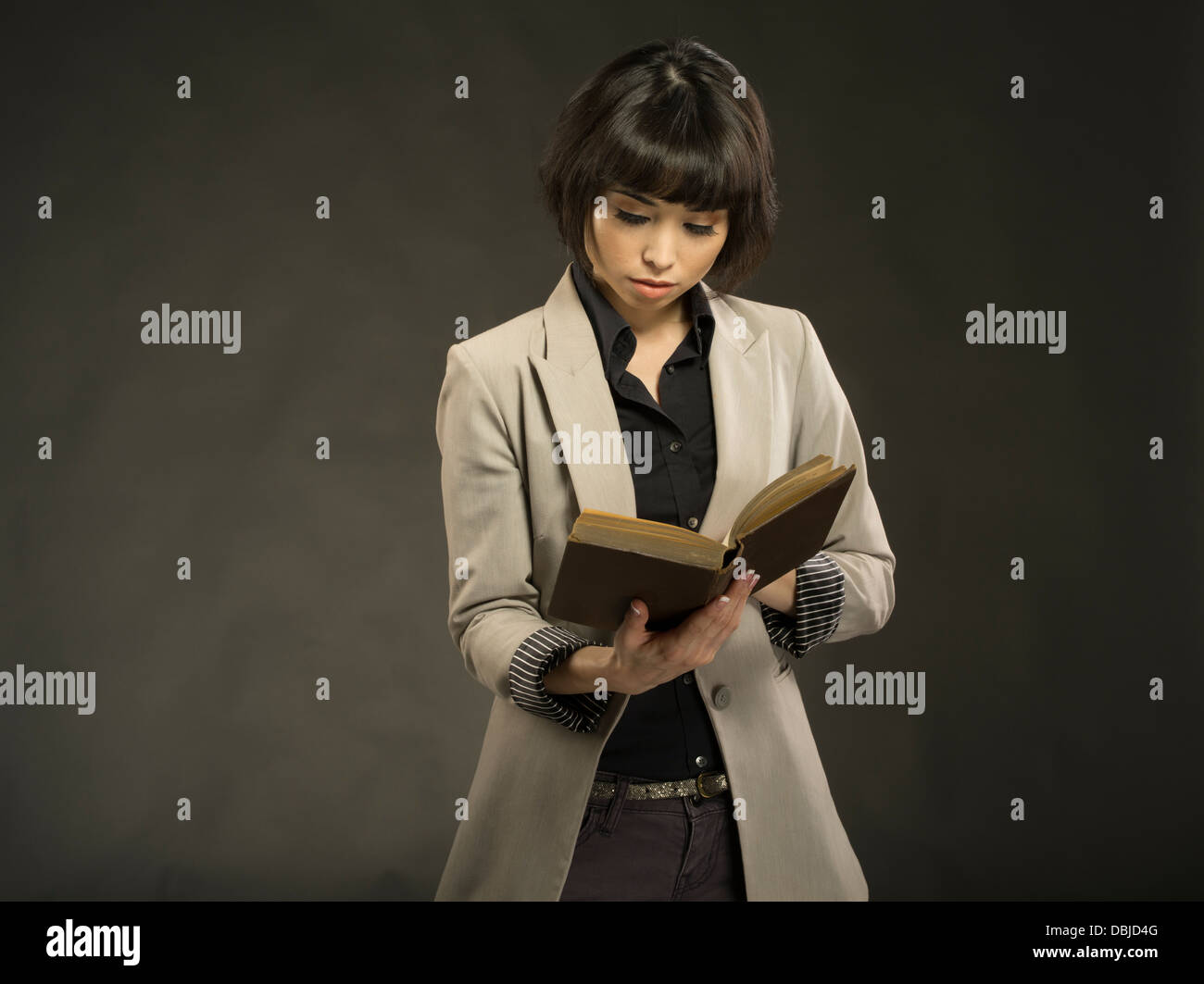 Young beautiful woman in her twenties reading old hardback book Stock Photo