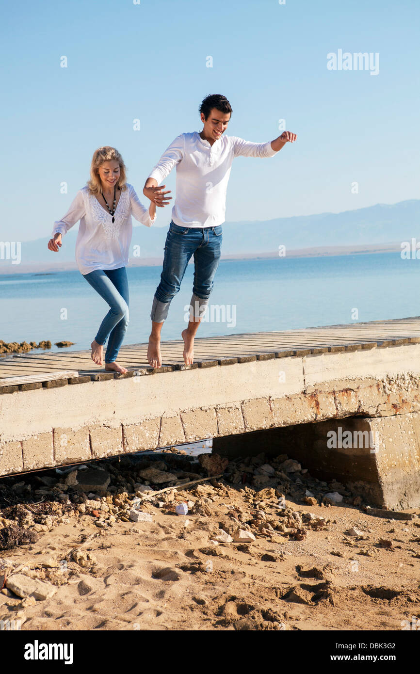 Croatia, Young couple jumping on beach Stock Photo