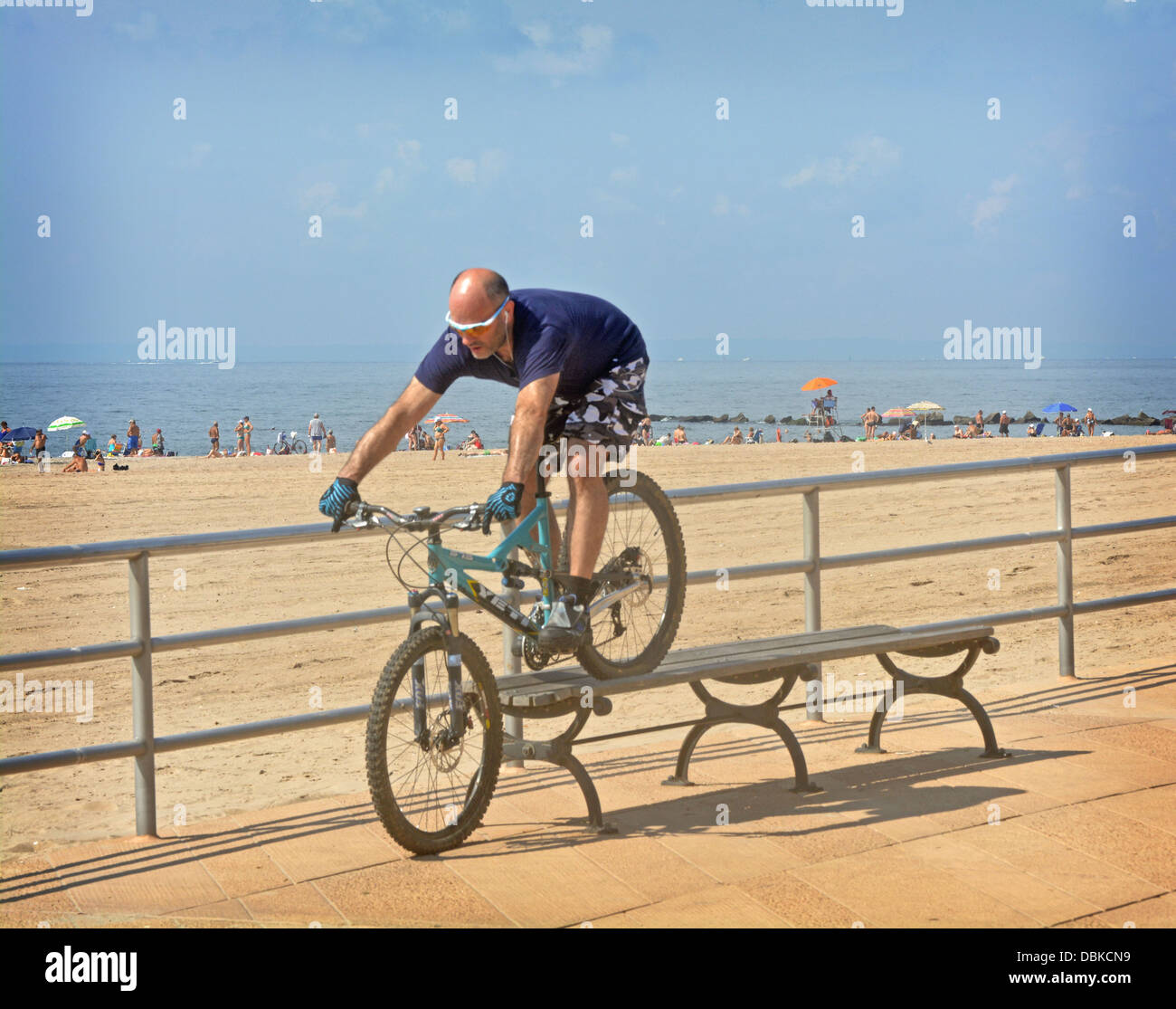 BIcycle stunt. A man riding his bike over a bench on the boardwalk in Brighton Beach Brooklyn, New York Stock Photo