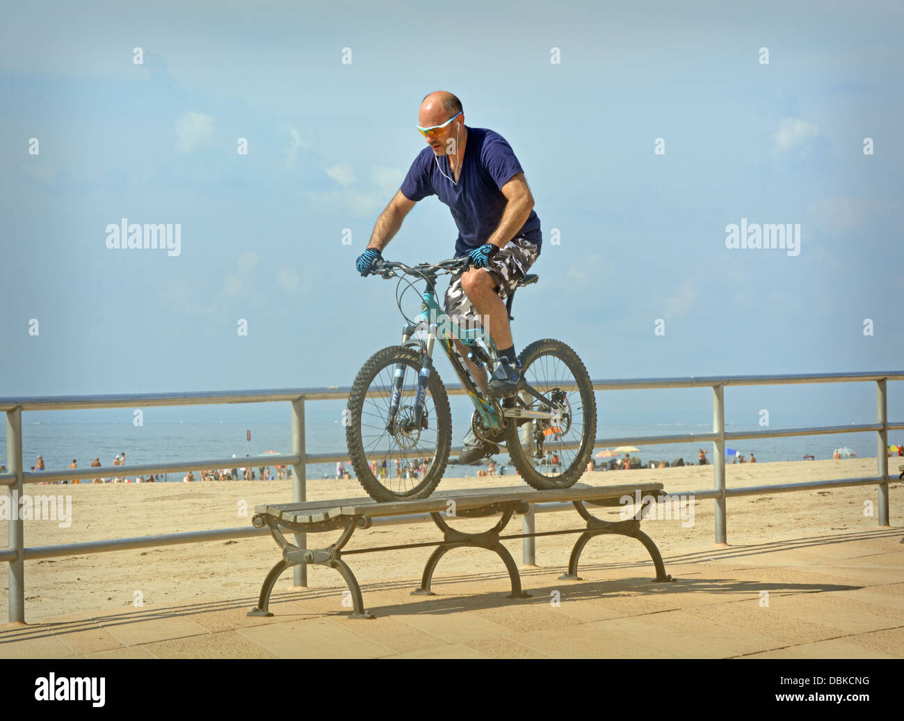 BIcycle stunt. A man riding his bike over a bench on the boardwalk in Brighton Beach Brooklyn, New York      v Stock Photo
