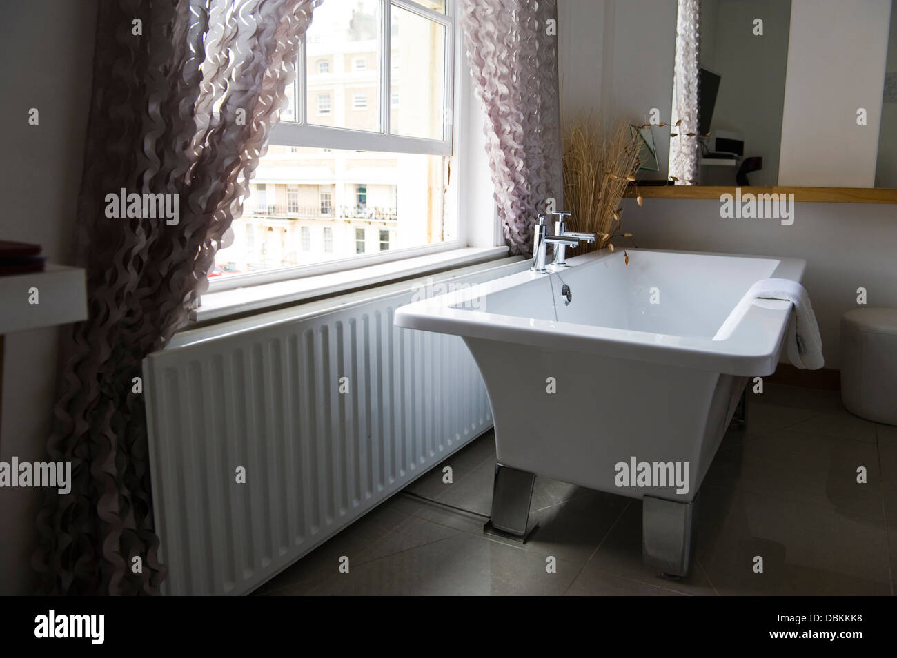 Bedroom of hotel with bath under window in Brighton East Sussex England UK Stock Photo