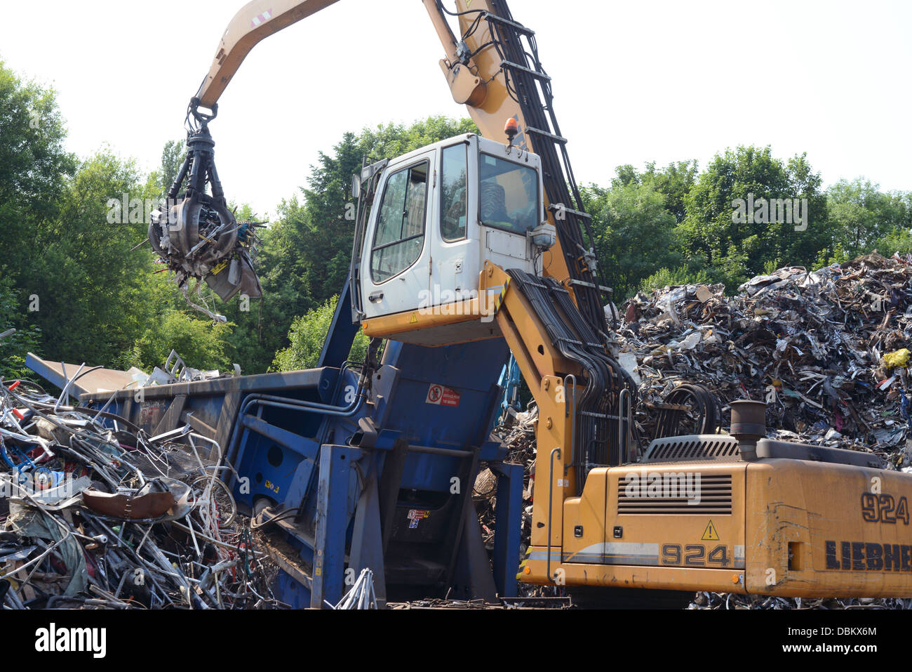 crane loading scrap metal into compactor at scrapyard for baling before being transported for re-smelting united kingdom Stock Photo
