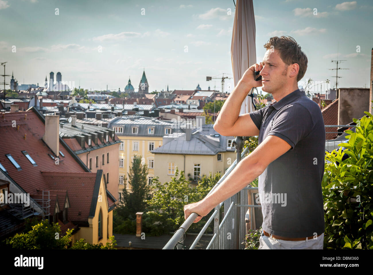 Man On Balcony Using Mobile Phone, Munich, Bavaria, Germany, Europe Stock Photo