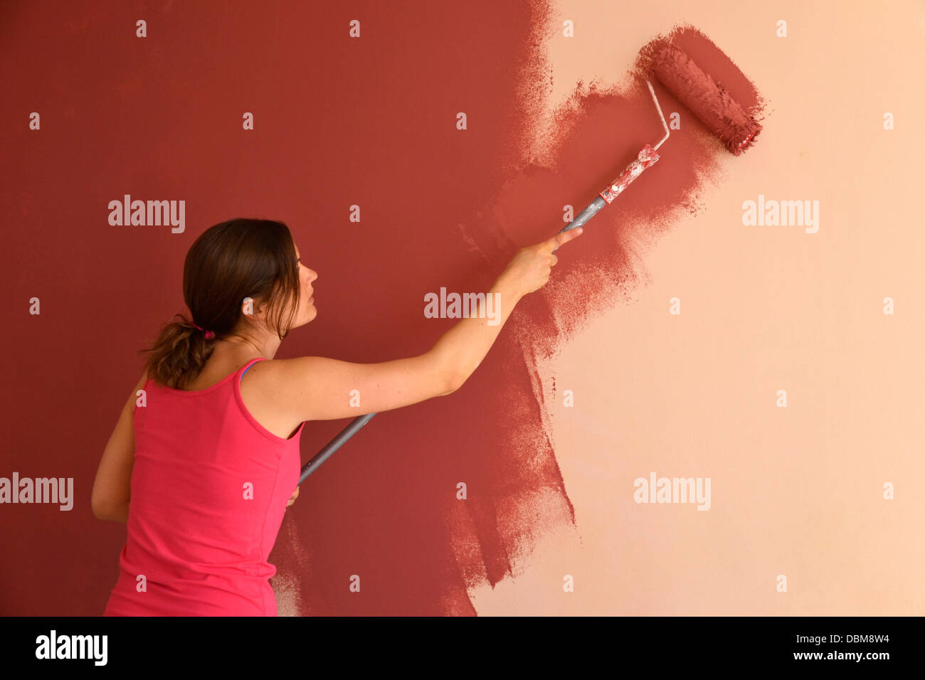 Beautiful Young Woman In Causal Clothes Painting A Wall With Red