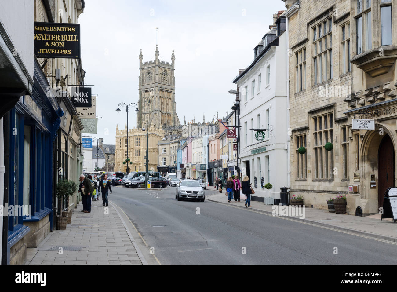 Shops on Dyer Street in Cirencester with St John The Baptist Church in
