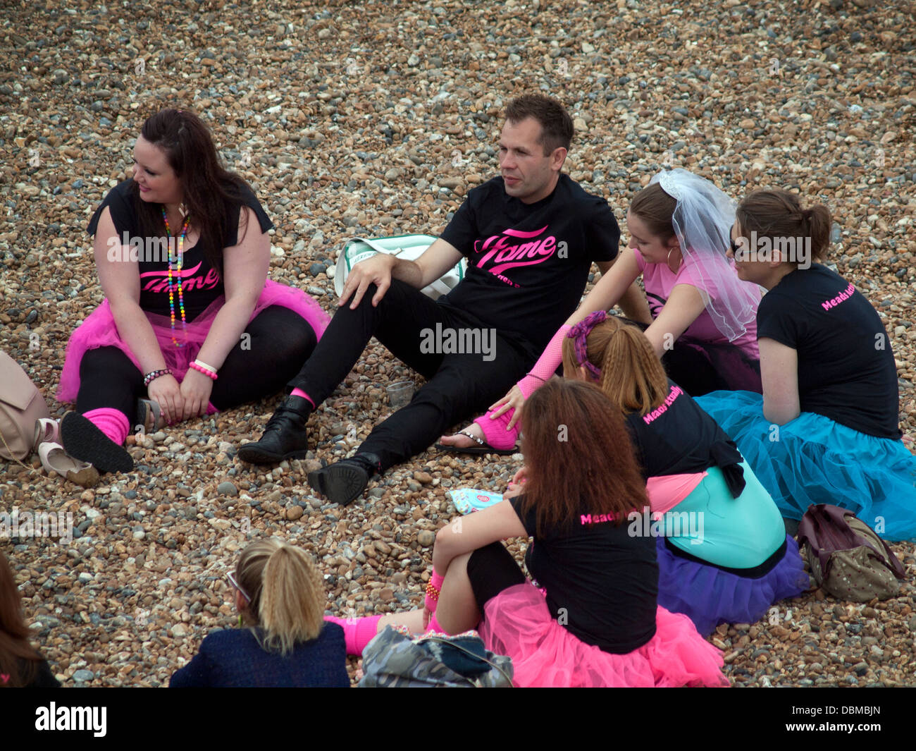 A hen party with a male friend sits on the beach in Brighton Stock Photo