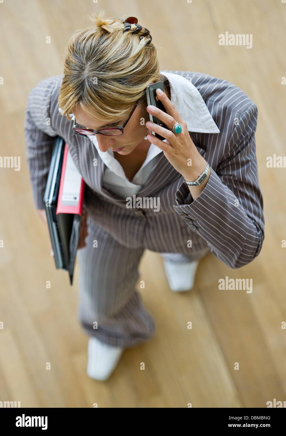(ILLUSTRATION) An illustration shows a business woman with a folder and laptop under her arm while talking on a smartphone in Frankfurt Oder, Germany, 31 July 2013. Photo: PATRICK PLEUL Stock Photo