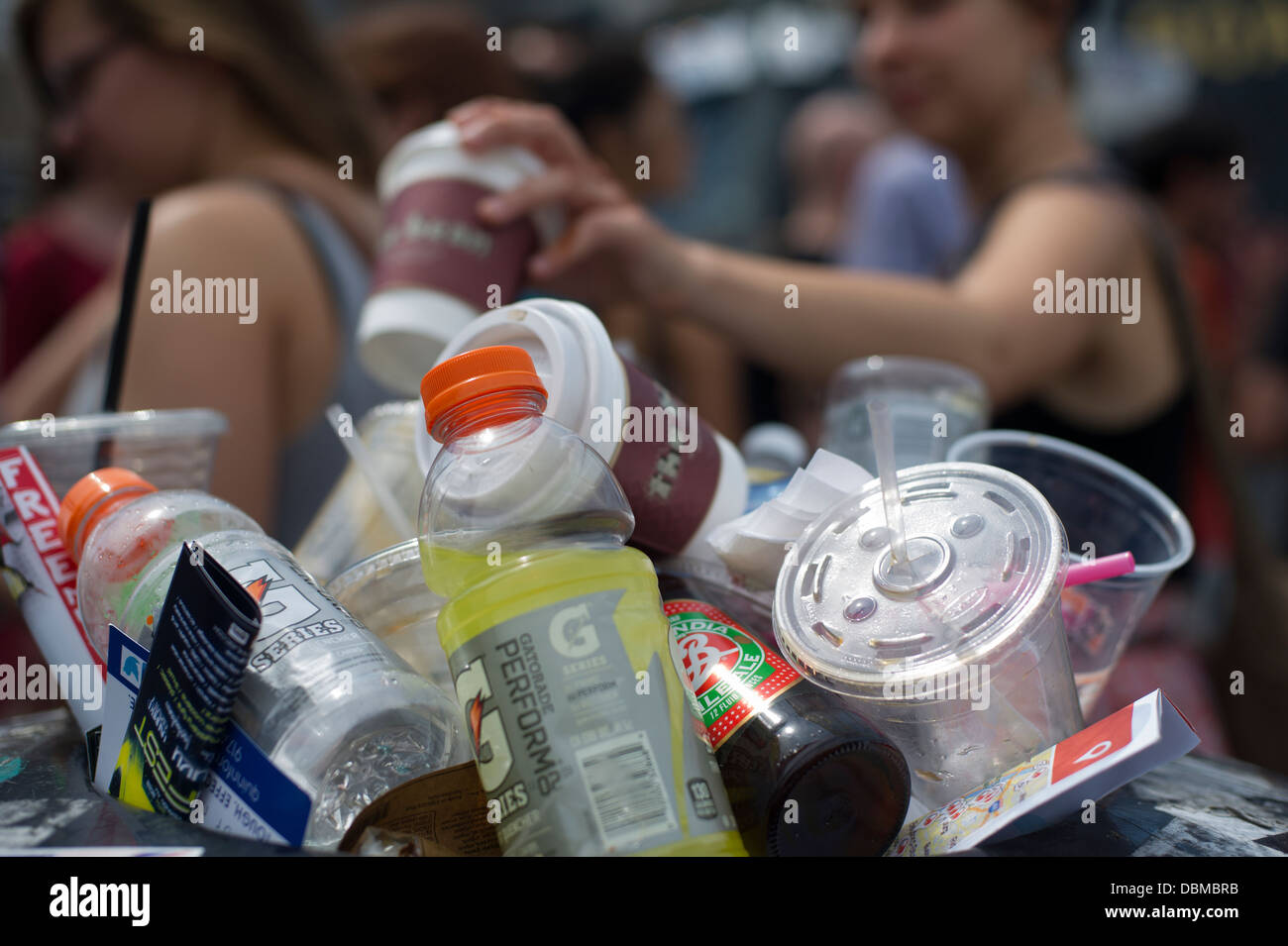 A passerby disposes of a paper coffee cup at an overflowing trash ...