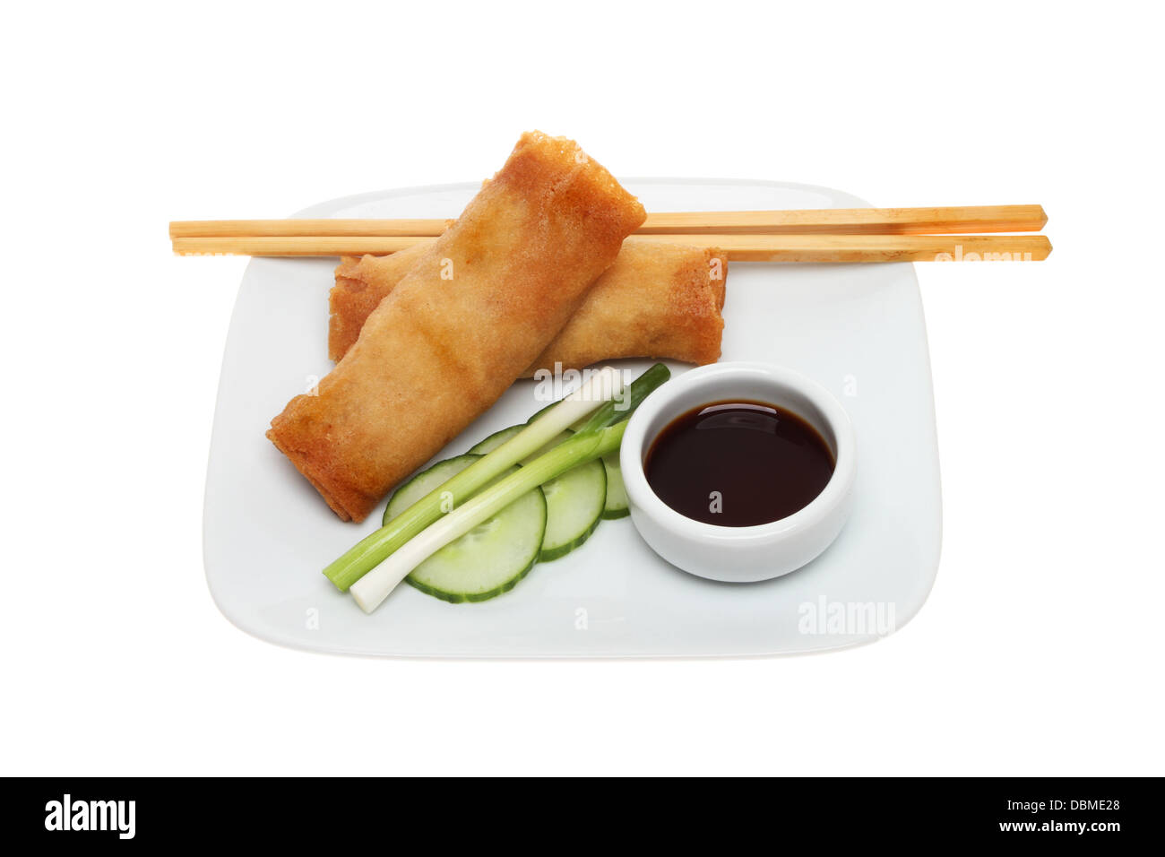 Pancake rolls, salad, soy sauce and chopsticks on a plate isolated against white Stock Photo