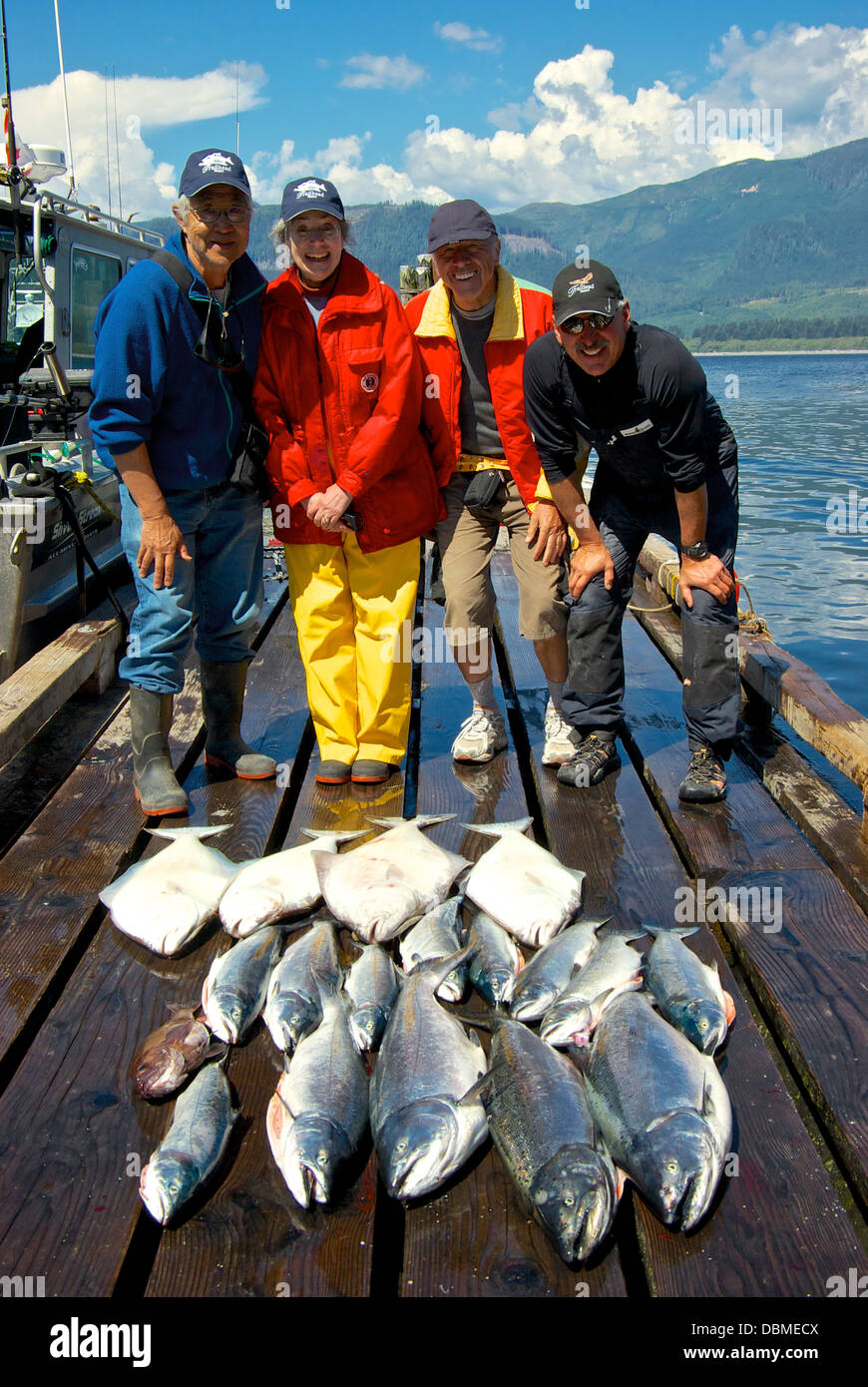 Group of anglers posing with big sport catch of hatchery chinook coho halibut Port Renfrew BC Canada fishing wharf Stock Photo