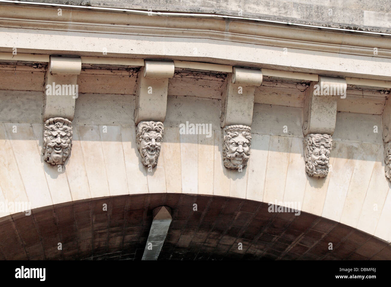 Amusing face masks on the Pont Nerf stone arched bridge viewed from the River Seine in Paris, France. Stock Photo