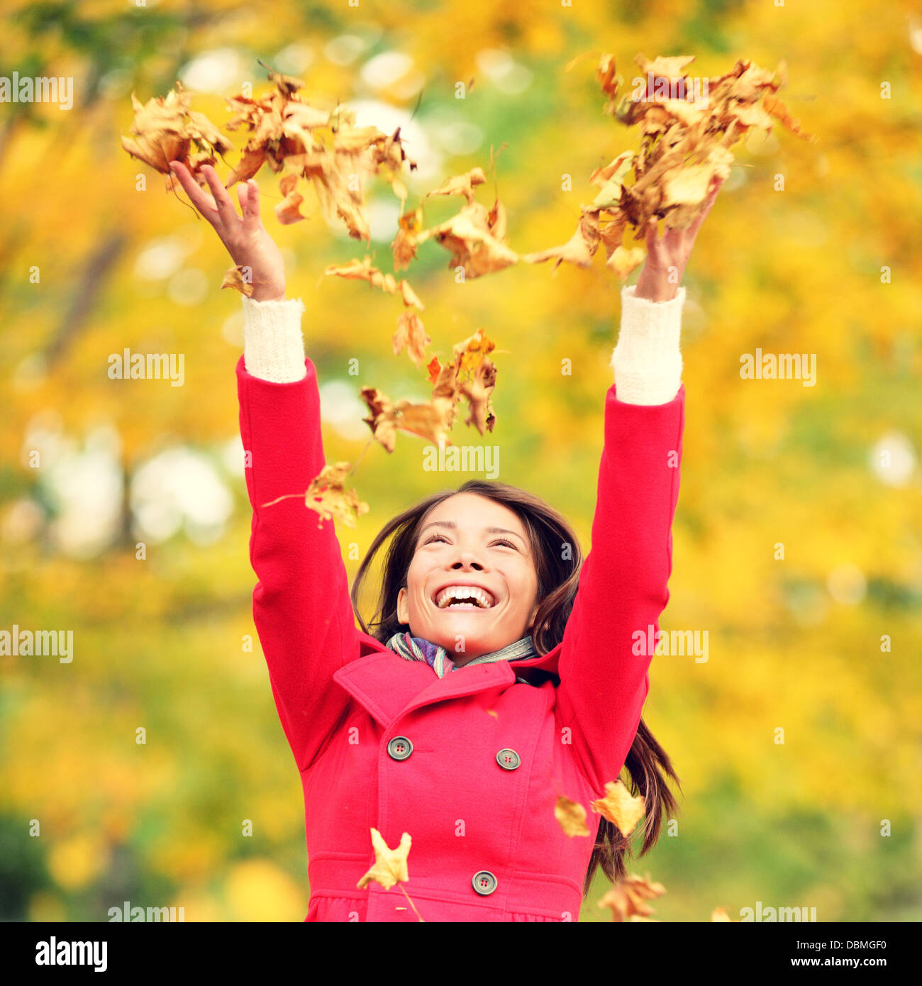 Autumn / fall woman happy throwing leaves up in the air with arms ...