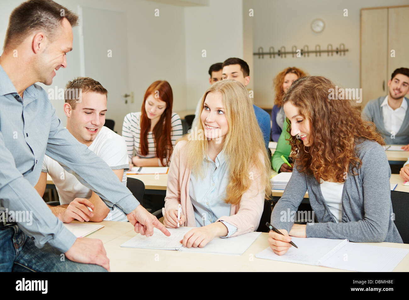 Teacher helping students in university seminar class Stock Photo - Alamy