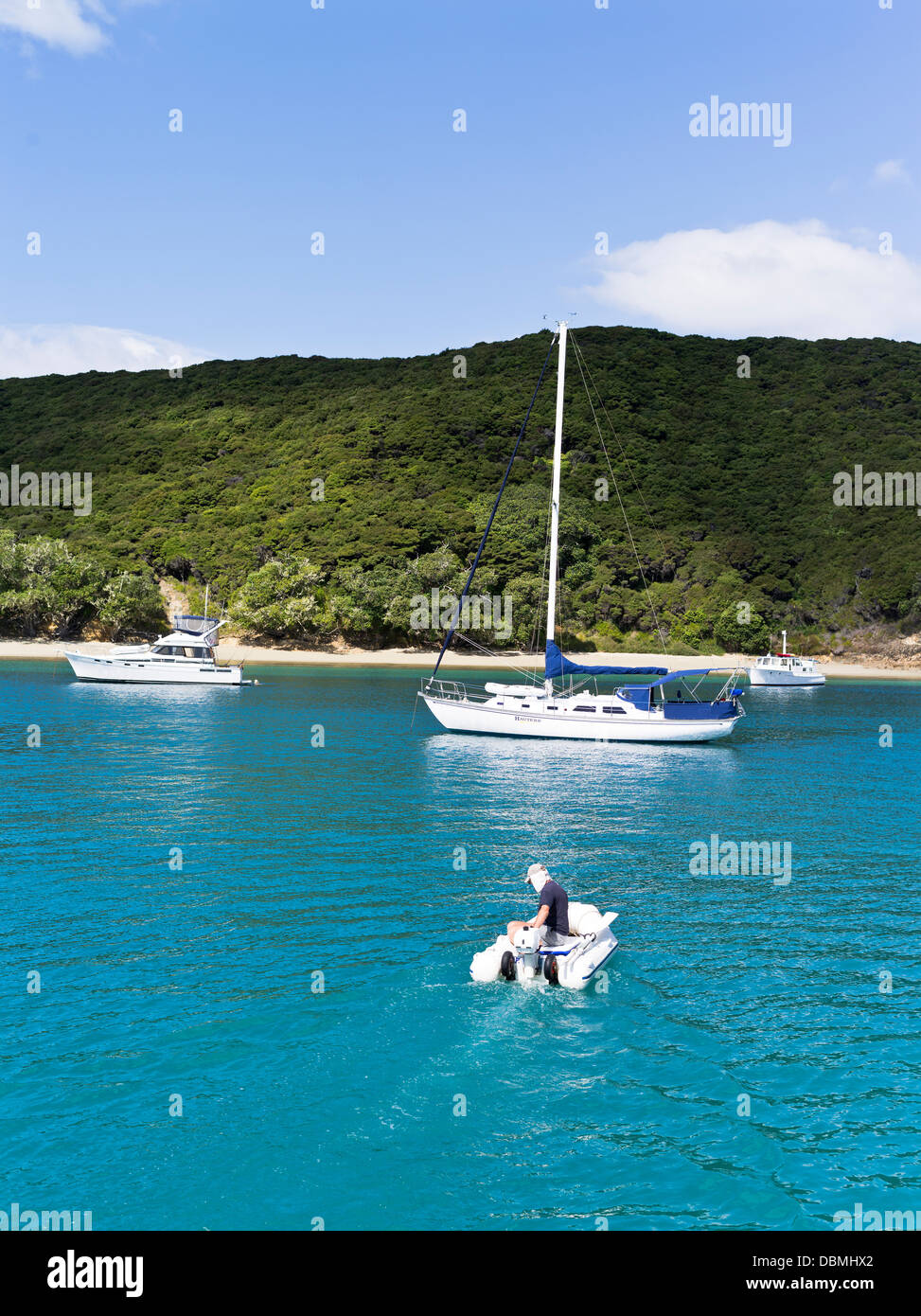 dh Urupukapuka Island anchorage BAY OF ISLANDS NEW ZEALAND Man in motor dinghy sailing and cruiser yachts anchored off shore yacht leisure Stock Photo