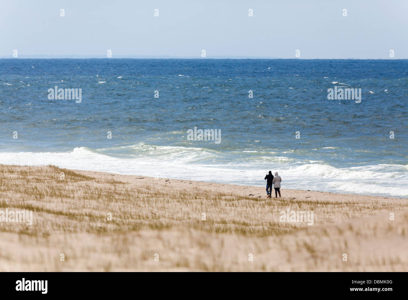 A couple walking and strolling along the ocean shore sandy beach Stock ...