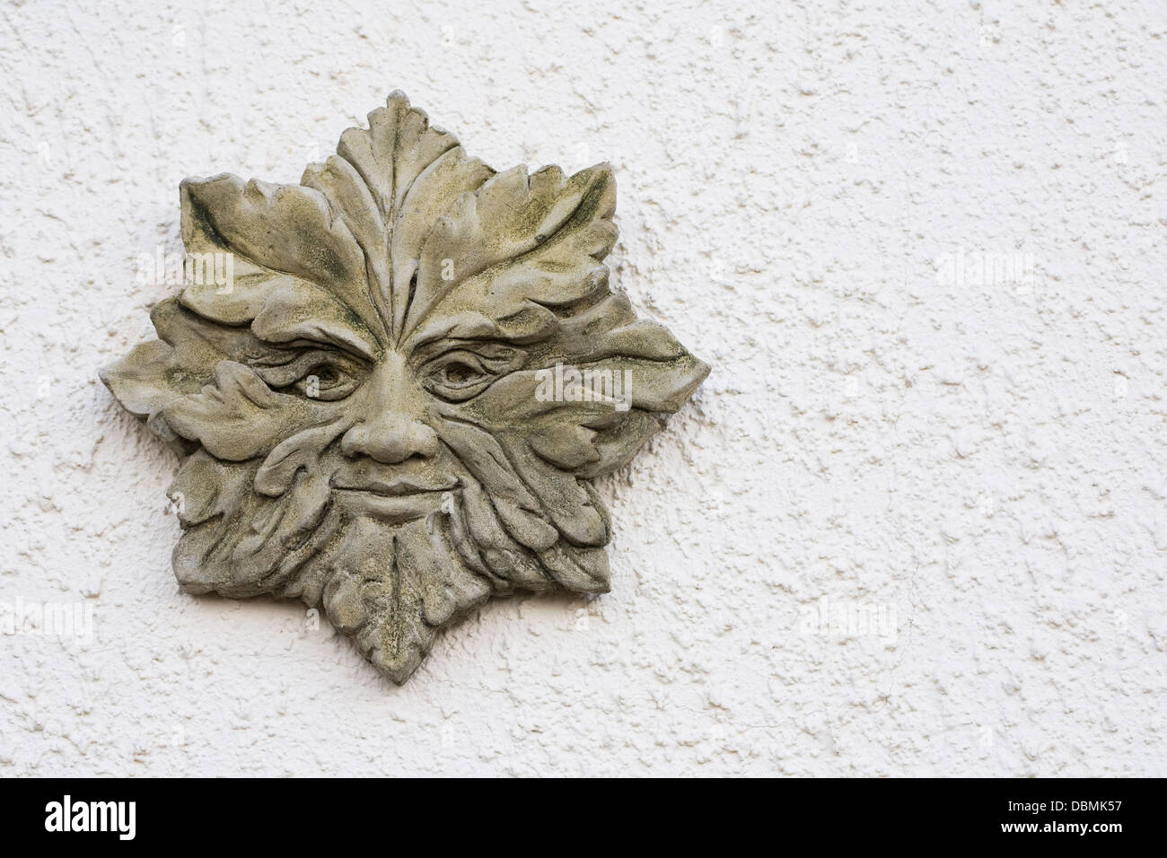 Green Man plaque on a white textured wall. Stock Photo